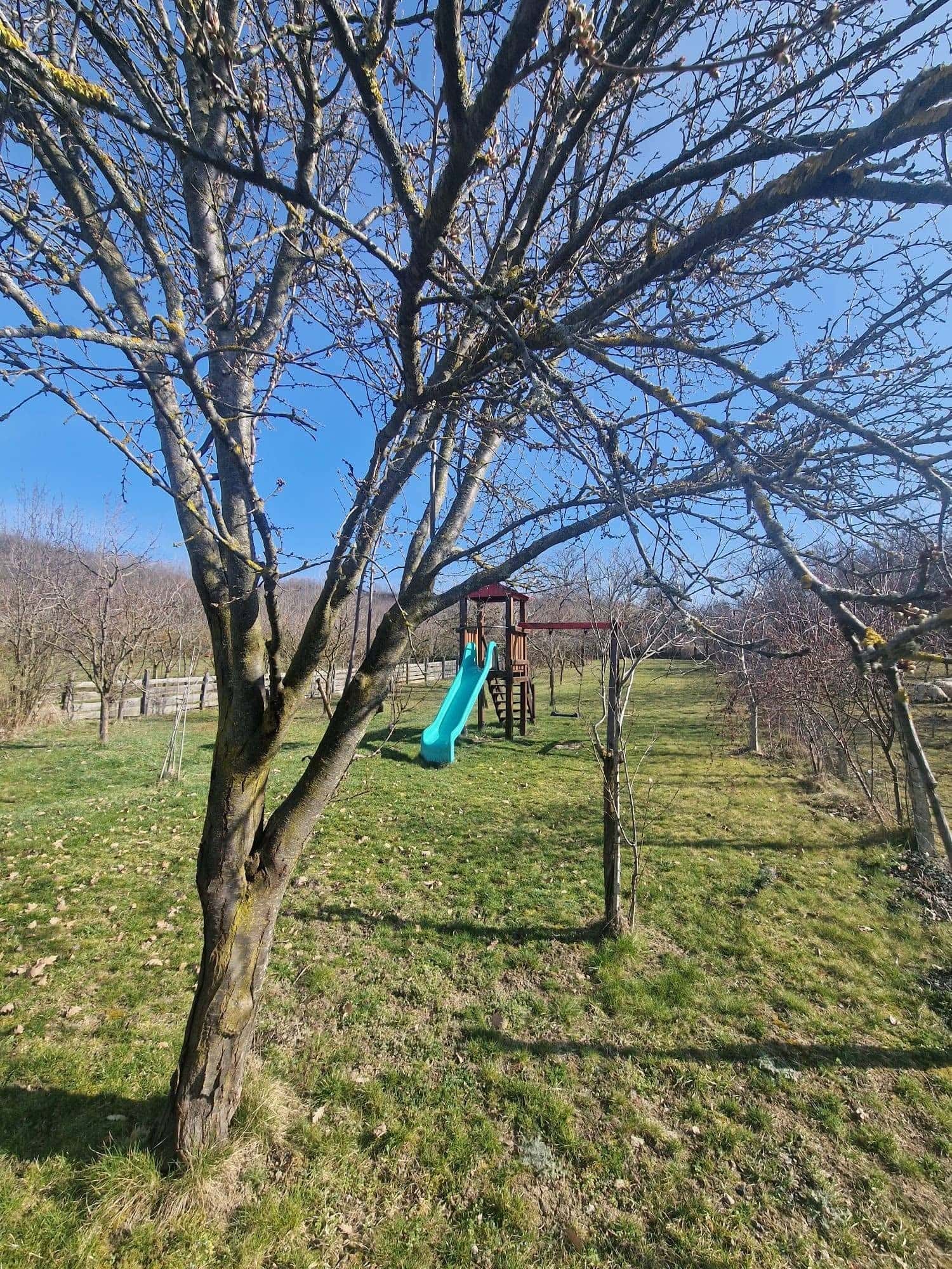 Livada la început de primăvară, cu tobogan în depărtare