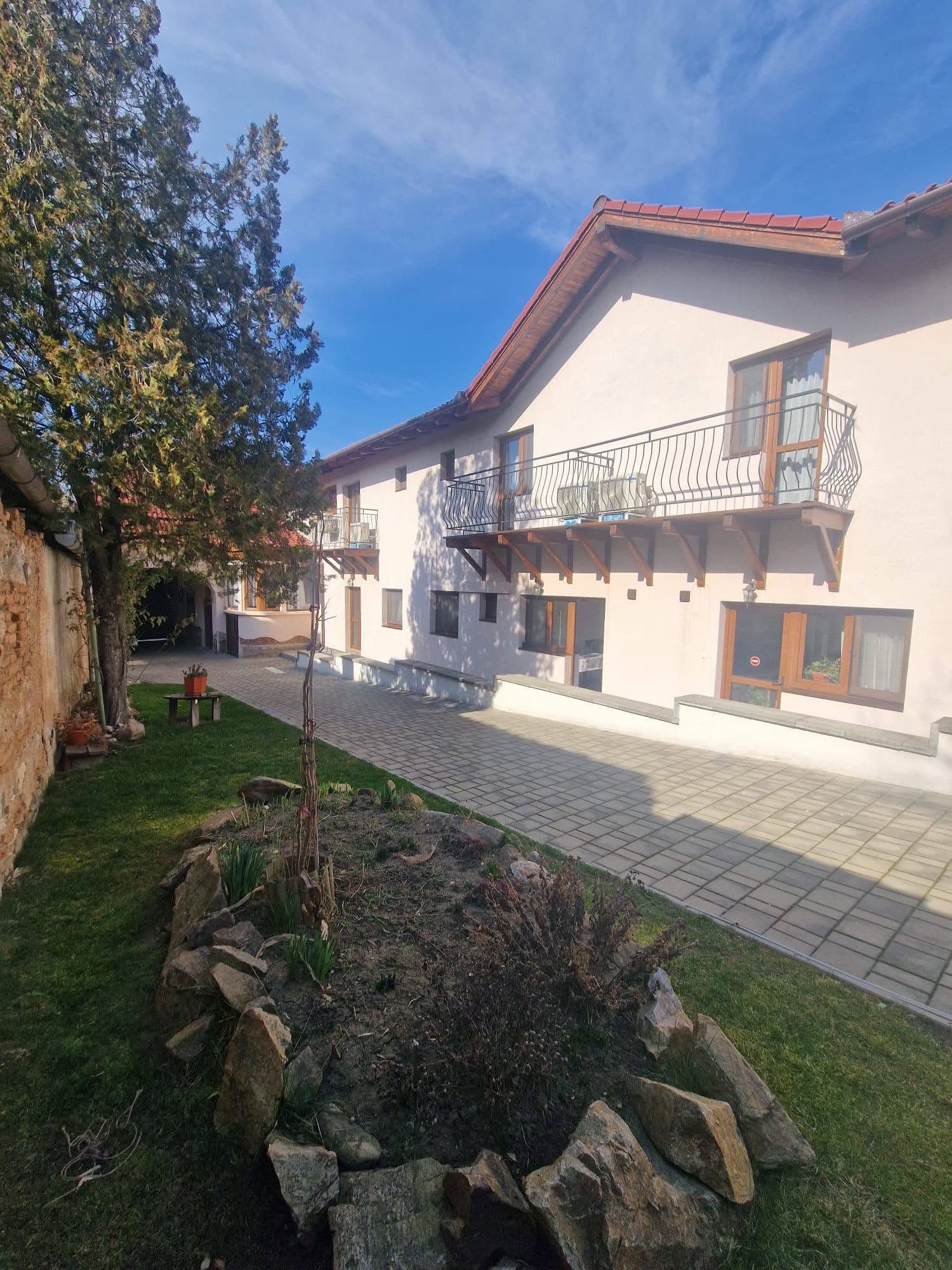 Clădirea văzută din grădină, cu un strat de flori cu pietre