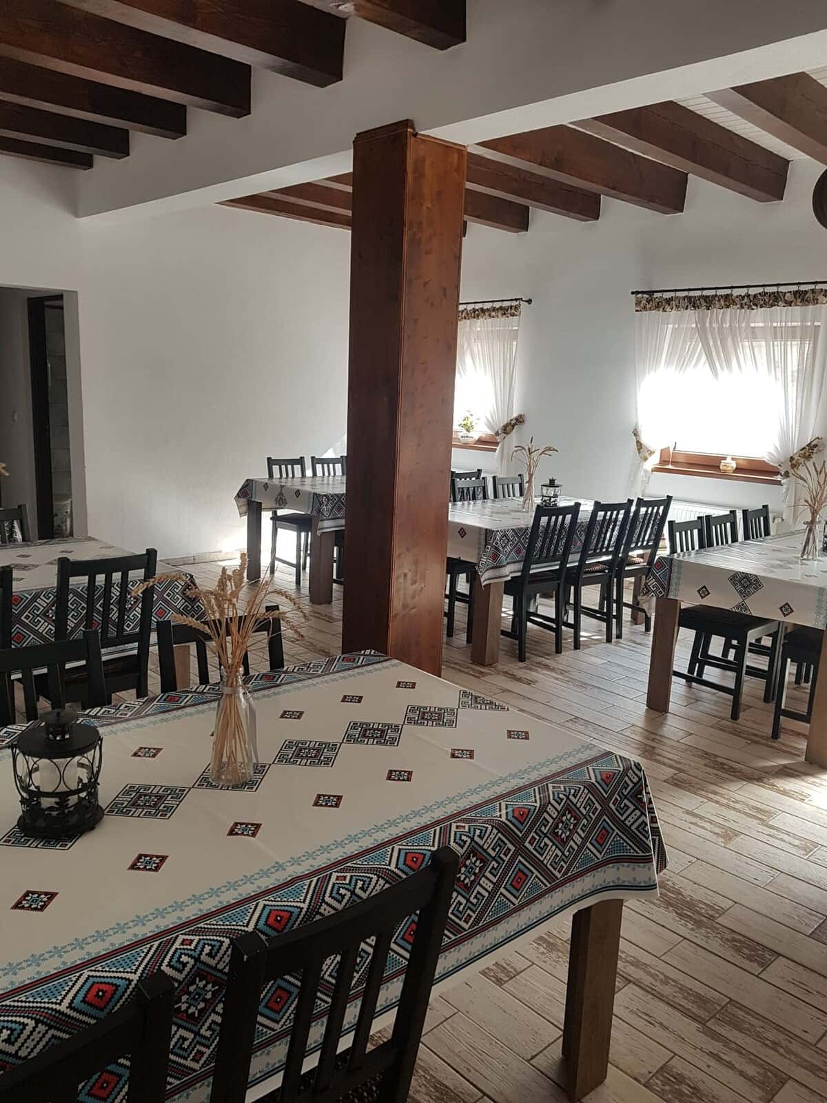 Sala de mese cu grinzi din lemn și fețe de masă cu motive tradiționale